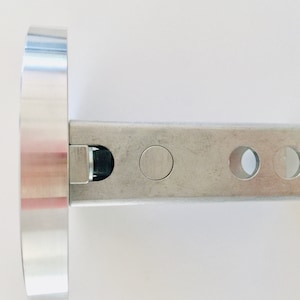 May include: Silver metal hitch receiver extension with a round plate on one end and three holes on the other end.