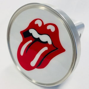 May include: A round, silver-colored object featuring the iconic red lips and tongue logo on a white background. The logo is a bold, graphic design with black accents. The object has a cylindrical handle.