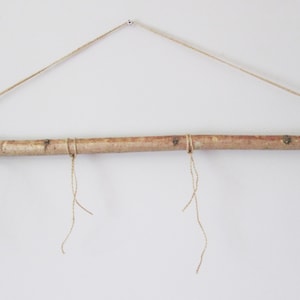May include: A natural wood branch with twine hanging from it. The branch is suspended from the ceiling with twine.