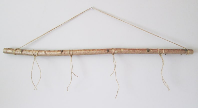 May include: A natural wood branch with twine hanging from it. The branch is suspended from the ceiling with twine.