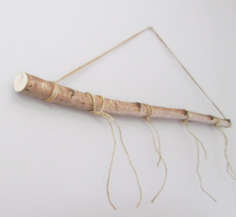 May include: A natural wood branch with twine wrapped around it, hanging from the ceiling. The twine is tied in knots and hangs down from the branch, creating a rustic and decorative look.