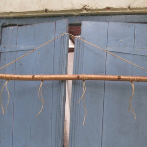 May include: A wooden dowel rod with four strings attached to it, hanging from a blue wooden door.