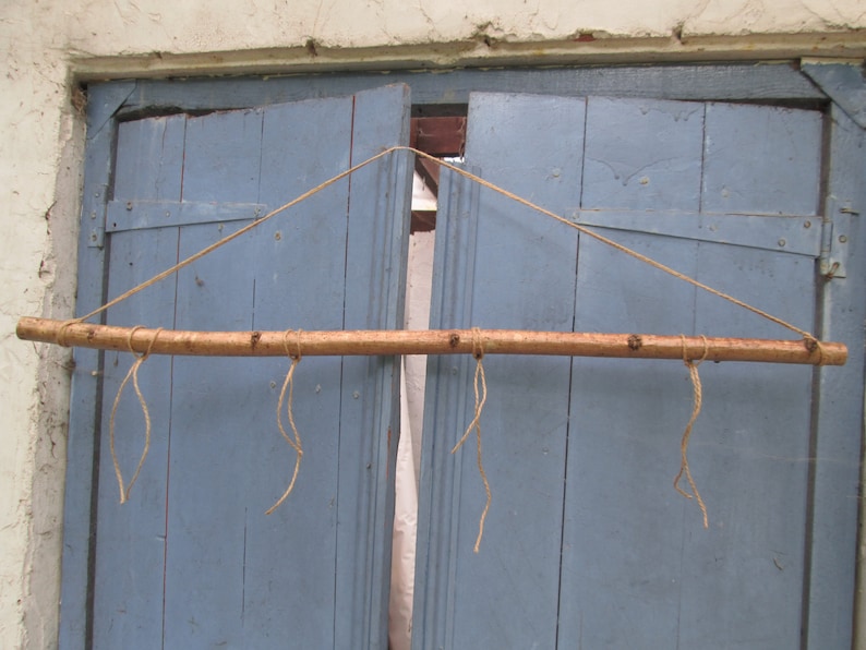 May include: A wooden dowel rod with four strings attached to it, hanging from a blue wooden door.