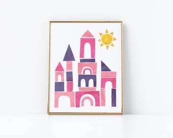 May include: Watercolor print of a castle made of building blocks in shades of pink, purple, and white, with a yellow sun in the upper right corner. The artwork is framed in a gold-colored frame.