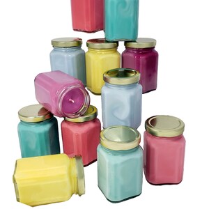 Puede incluir: Una colecci&oacute;n de 10 velas coloridas en frascos de vidrio con tapas doradas. Las velas est&aacute;n dispuestas en forma de pir&aacute;mide, con la vela superior de color rosa, la siguiente capa de color azul, amarillo y morado, y la capa inferior de color verde azulado, rosa, azul, rosa, amarillo y verde azulado.