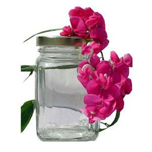 Puede incluir: Un tarro de vidrio transparente con tapa dorada, lleno de un l&iacute;quido transparente. Un racimo de flores de guisante dulce rosas se apoya en el tarro.