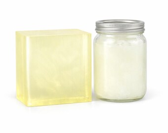May include: A large, translucent, pale yellow rectangular block of soap positioned next to a clear glass mason jar filled with a white, opaque substance and topped with a silver-coloured metal screw-on lid against a plain white background.