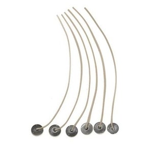 Puede incluir: Siete mechas de vela blancas con bases de metal. Las mechas son curvas y las bases son redondas y plateadas.