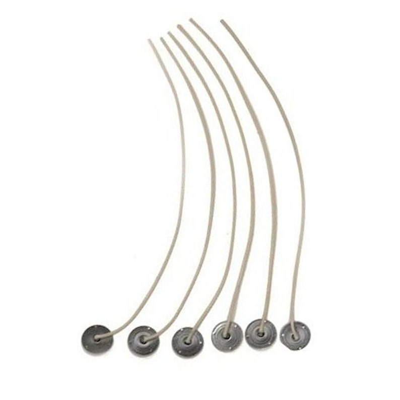 Puede incluir: Siete mechas de vela blancas con bases de metal. Las mechas son curvas y las bases son redondas y plateadas.