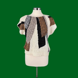 May include: A white short-sleeved sweater with a geometric pattern in brown, black, and gray.