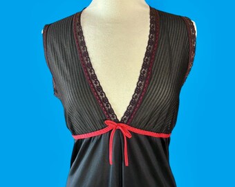 May include: A sleeveless black nightgown featuring a deep V-neckline trimmed with dark lace and a bright red ribbon tie at the empire waist. The bodice has a vertical ribbed texture, while the skirt portion is smooth and solid black fabric.