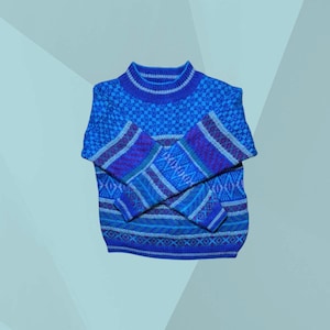 Könnte beinhalten: Ein blauer Strickpullover mit hohem Kragen und langen Ärmeln. Der Pullover hat ein geometrisches Muster in Blau-, Lila- und Weißtönen. Die Ärmel haben ein Streifendesign, und der Körper ist aus strukturiertem Strick.