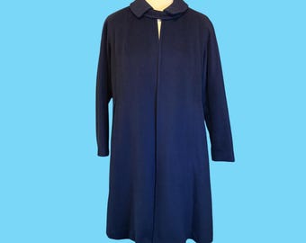 May include: A navy blue coat with a collar and long sleeves, displayed on a mannequin. The coat has a simple design and is set against a light blue background. A classic garment.
