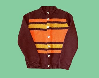 May include: A vintage-style, button-down cardigan sweater. The sweater features a dark brown body with horizontal stripes in orange and yellow across the chest. The sleeves are dark brown, and the sweater has white buttons.