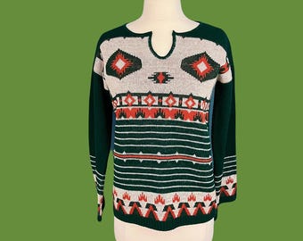 May include: A green, beige, and red patterned sweater with a keyhole neckline. The sweater has a geometric design.