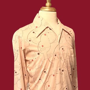 May include: A cream-colored button-down shirt with a geometric pattern of brown lines and red and brown squares. The shirt has a classic collar and a single chest pocket. The shirt is displayed on a mannequin.