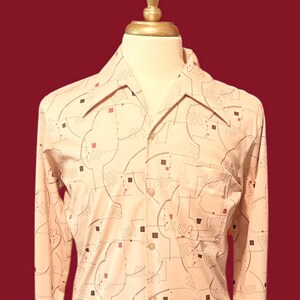 May include: A vintage button-down shirt with a cream-colored base and a repeating pattern of abstract shapes in brown, red, and gray. The shirt features a single chest pocket and a wide collar, typical of the era.
