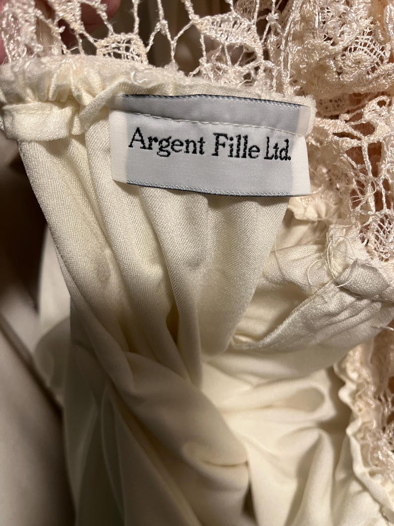 Pode incluir: Um top branco de renda com uma etiqueta branca que diz "Argent Fille Ltd."