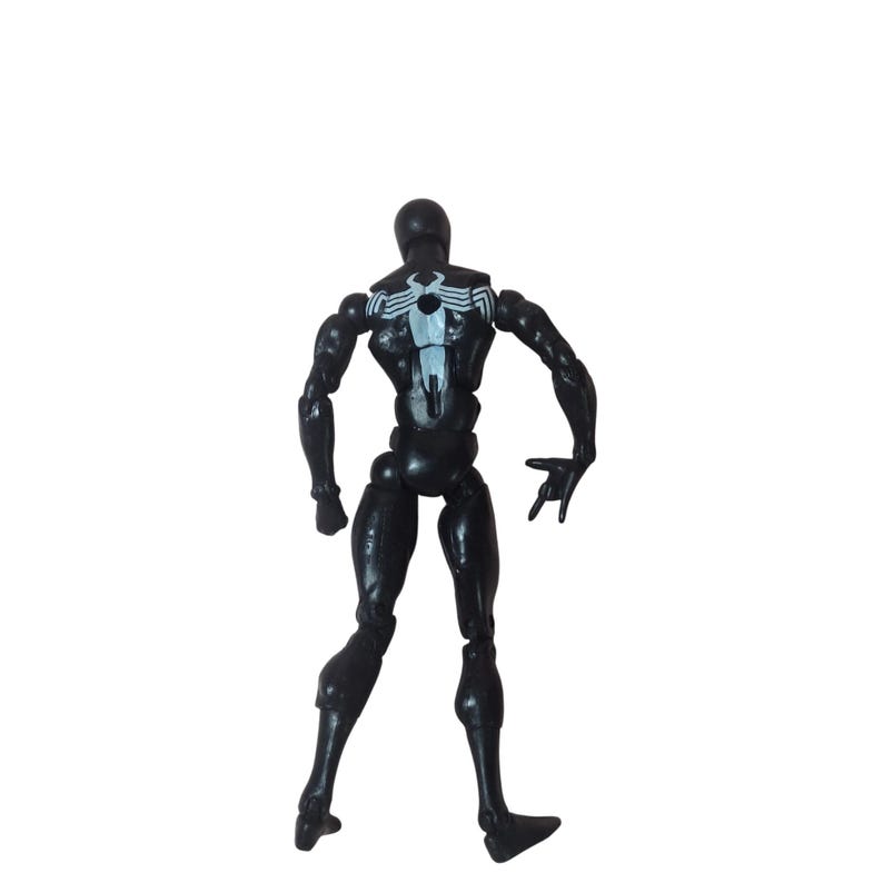 Peut inclure: Figurine d'action noire d'un super-h&eacute;ros, vue de dos. La figurine porte un embl&egrave;me d'araign&eacute;e blanc sur le dos et est pos&eacute;e avec une main ouverte. La figurine est articul&eacute;e au niveau des articulations.