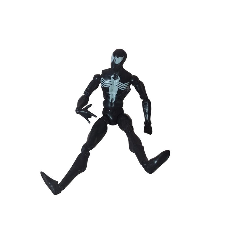 Peut inclure: Figurine d'action noire repr&eacute;sentant un super-h&eacute;ros dans une pose dynamique. La figurine arbore un embl&egrave;me d'araign&eacute;e blanc sur la poitrine et un motif en forme d'araign&eacute;e blanc sur la t&ecirc;te. Les membres sont articul&eacute;s.