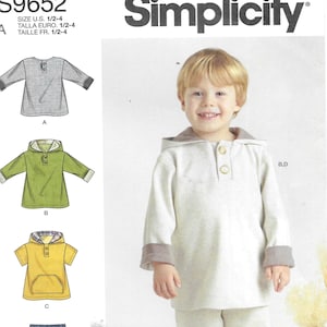 May include: Simplicity pattern S9652 for children's clothing. The image shows a child wearing a light gray hooded sweatshirt and pants. The pattern includes options for a long-sleeved shirt, a hooded shirt, a short-sleeved shirt, and pants. Easy-to-sew design.