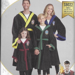 May include: A Simplicity sewing pattern for Harry Potter robes. The pattern includes four robes in black, green, and burgundy with yellow, green, and red trim. The robes feature the Hogwarts house crests. The pattern is for sizes XS-L/XS-XL.