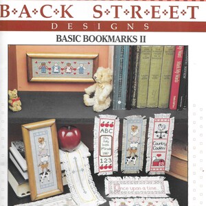 May include: A set of 6 cross-stitch bookmark patterns featuring various themes, including ABCs, farm animals, and a fairytale scene. The patterns are printed on a white background with red, blue, and green accents. The title "Basic Bookmarks II" is printed at the top of the page.