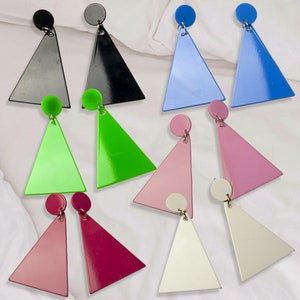 May include: A set of 10 triangle-shaped earrings in various colors, including black, blue, green, pink, white, and red. The earrings are made of a shiny, glossy material and have a simple, geometric design.