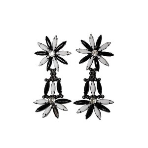 Puede incluir: Un par de pendientes colgantes negros y blancos con un diseño de flores. Los pendientes tienen un pequeño cristal en el centro de cada flor.