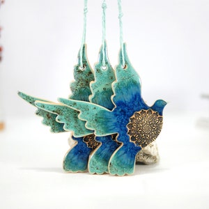 May include: Three ceramic dove ornaments with blue and green glaze and intricate gold details. The doves are hanging from twine.