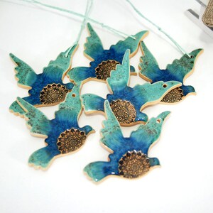 May include: Six blue and green ceramic bird ornaments with gold accents. Each bird has a mandala design on its chest.