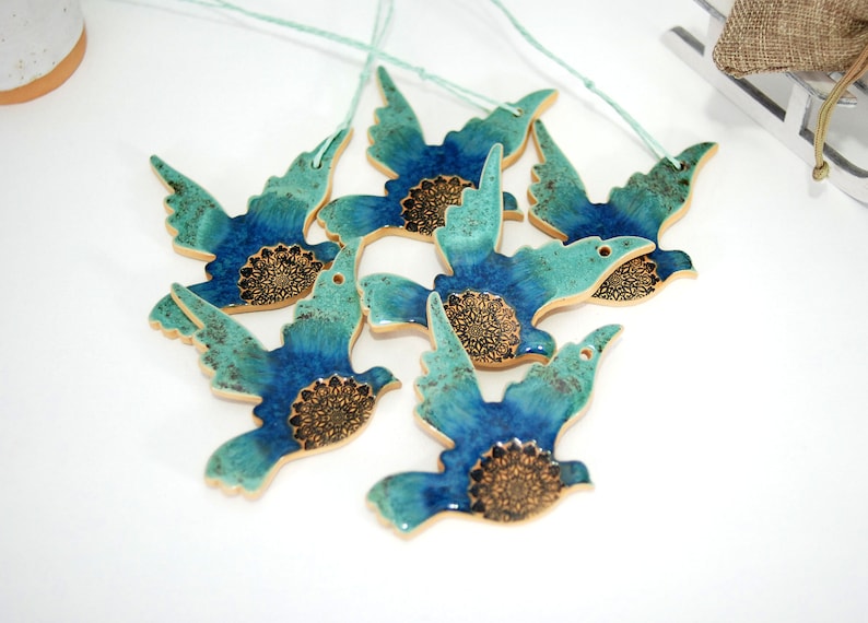 May include: Six blue and green ceramic bird ornaments with gold accents. Each bird has a mandala design on its chest.