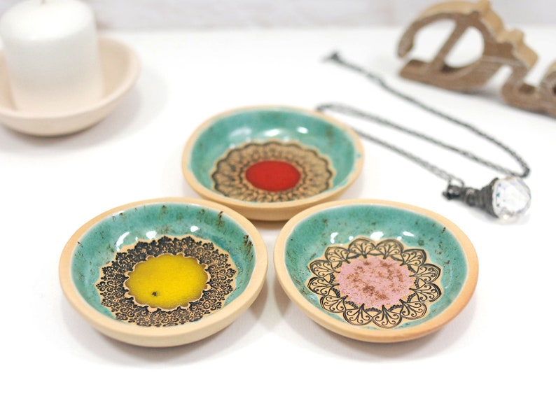 Peut inclure: Trois petits plats en c&eacute;ramique avec un gla&ccedil;age vert turquoise et des motifs de mandalas noirs. Chaque plat a un centre de couleur diff&eacute;rente&nbsp;: rouge, jaune et rose.