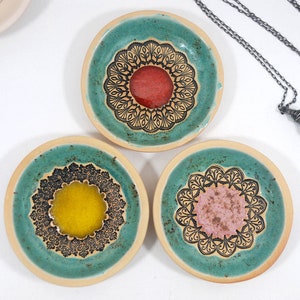 Peut inclure: Trois petits plats en c&eacute;ramique avec un gla&ccedil;age vert turquoise et des motifs de mandalas noirs. Chaque plat a un centre de couleur diff&eacute;rente&nbsp;: rouge, jaune et rose.