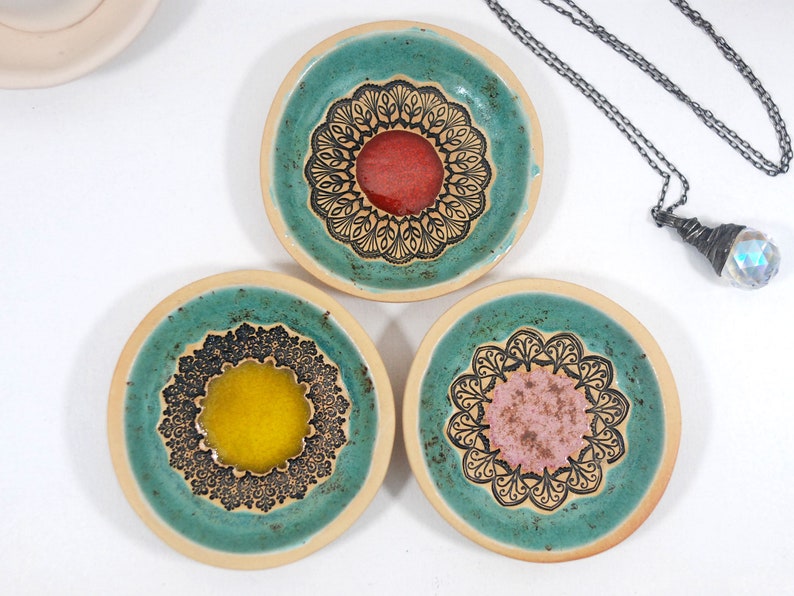 Peut inclure: Trois petits plats en c&eacute;ramique avec un gla&ccedil;age vert turquoise et des motifs de mandalas noirs. Chaque plat a un centre de couleur diff&eacute;rente&nbsp;: rouge, jaune et rose.