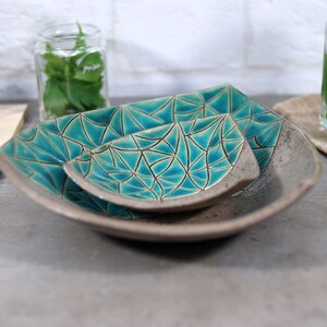 May include: Three ceramic bowls with a geometric pattern in shades of teal and gray. The bowls are nested together, with the smallest bowl on top.