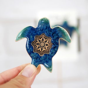 May include: A blue and green ceramic turtle with a gold mandala design on its shell.