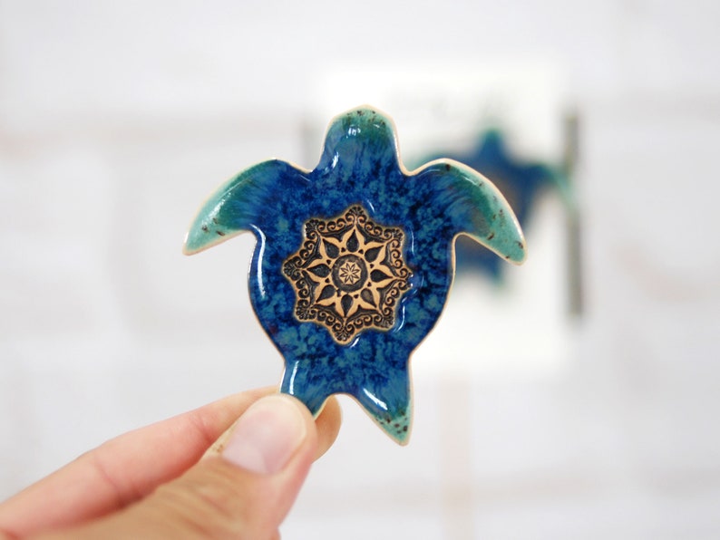 May include: A blue and green ceramic turtle with a gold mandala design on its shell.