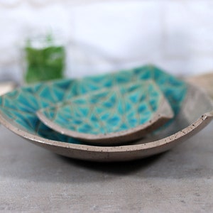 May include: Two gray ceramic serving dishes with a teal geometric pattern. The dishes are stacked on top of each other.
