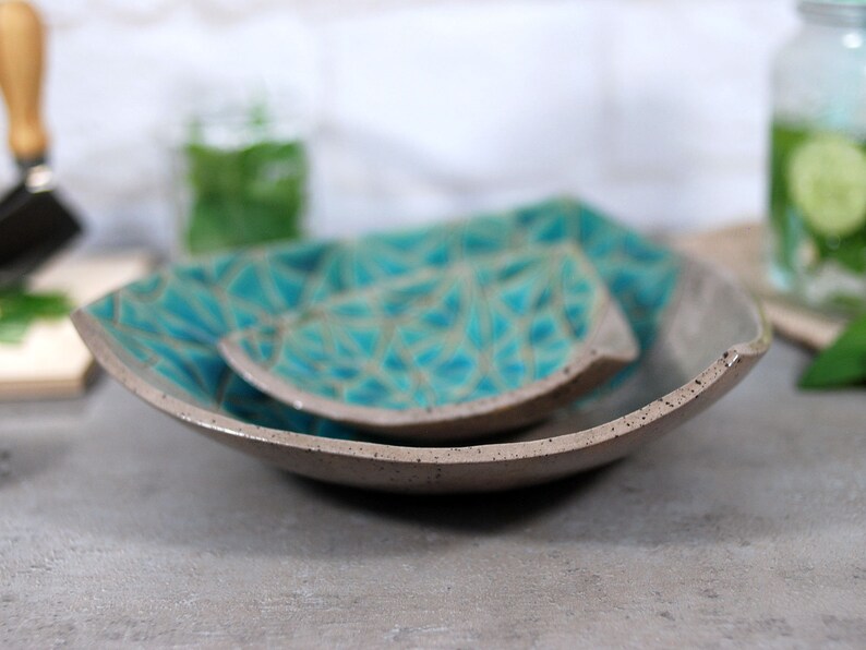 May include: Two gray ceramic serving dishes with a teal geometric pattern. The dishes are stacked on top of each other.