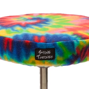 Może przedstawiać: Okrągłe, tie-dye wzorzyste siedzisko na tron bębna z czarną etykietą z napisem "Stone Thrones".