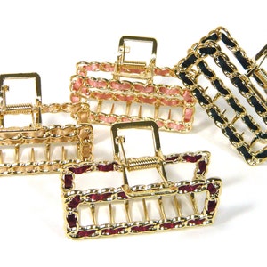 May include: Four gold hair clips with a chain link design. The clips have different colored accents: pink, black, burgundy, and black.