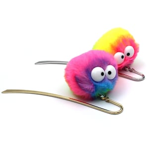 May include: Two colourful fuzzy bookmarks with large googly eyes. The bookmarks are attached to gold and silver metal bookmark holders.