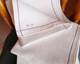 May include: Three white linen tea towels with red trim and the initials "M.V." embroidered in red on the top towel.