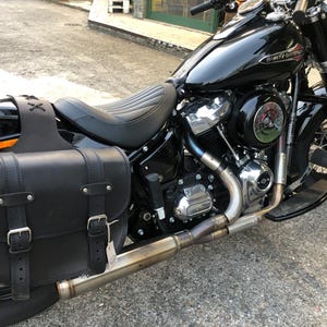 Könnte beinhalten: Schwarzes Motorrad mit einer schwarzen Ledertasche und einem verchromten Auspuff. Das Motorrad hat einen schwarzen Sitz und einen verchromten Motor.