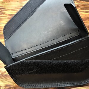May include: Black leather wallet with multiple compartments and a velcro closure.