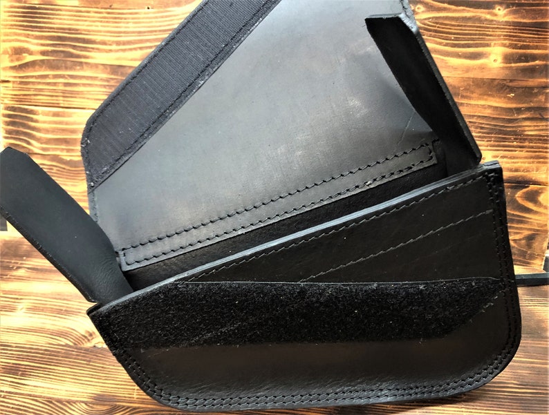 May include: Black leather wallet with multiple compartments and a velcro closure.