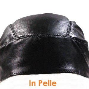 Peut inclure: Un do-rag en cuir noir avec une couture sur le bord. Le do-rag est plié en deux et le texte "In Pelle" est imprimé sur la surface blanche en dessous.