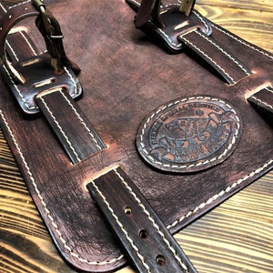 May include: Brown leather motorcycle saddlebags with white stitching and a circular leather patch that reads "HIRES SPECIAL SERVICE QUALITY MOTORCYCLE PARTS".