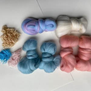 May include: A collection of colorful wool roving and fibers in various shades. The assortment includes light blue, pink, white, and beige wool, along with strands of blue and pink fibers. Ideal for crafting and textile projects.